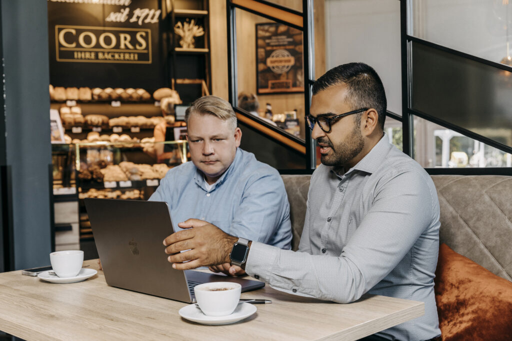 Eyüp Aramaz berät Kunden in einer Bäckerei vor dem Laptop