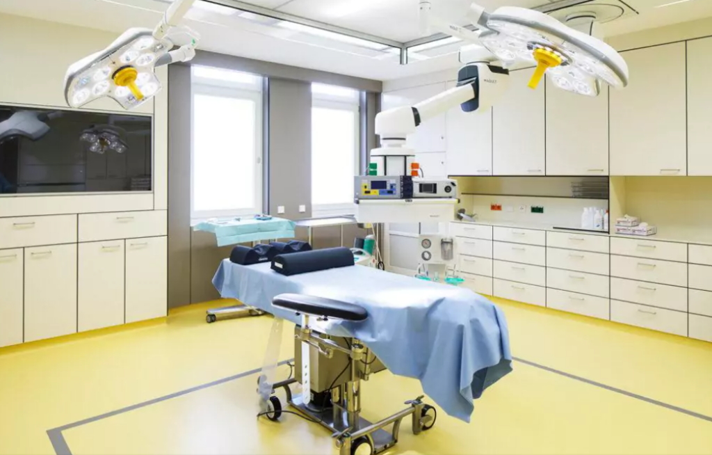 Ästhetische Chirurgie Wien Operationsraum mit Liebe und blauem Tuch darüber auf gelbem Fußboden. Darüber eine große Operationslampe